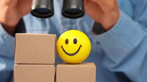 A person uses binoculars to examine e-commerce boxes.