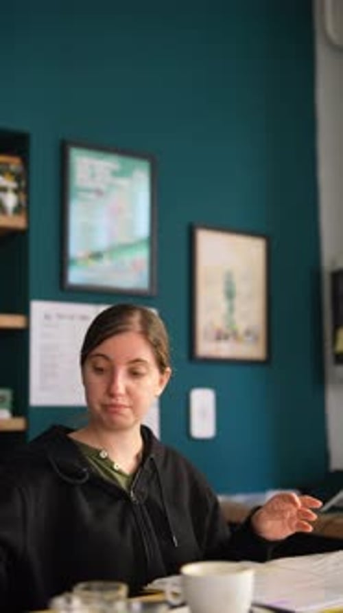 Young Woman Working in a Cozy Cafe Enjoying Coffee and Focusing on Tasks in a Relaxed Environment