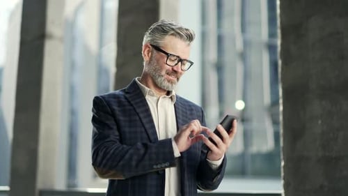 Portrait of handsome mature businessman entrepreneur hold smartphone scrolling browsing texting