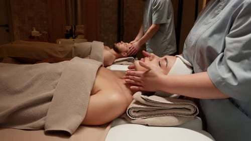 Relajante sesión de masaje de spa con terapeutas que masajean suavemente la cabeza y el cuello de los clientes durante el masaje