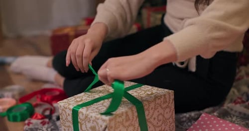 Woman Tying Green Ribbon on Holiday Gift Box