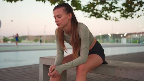 Tired Happy Woman Runner Taking a Rest After Run Sitting Bench Near Running Track Breathe Hard