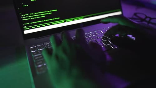 Person Coding on Laptop in Dark Room