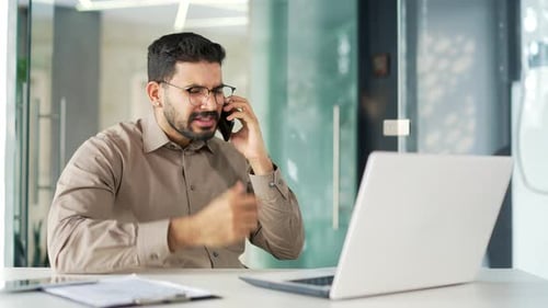 Angry Young Man Arguing on Phone at Office Desk
