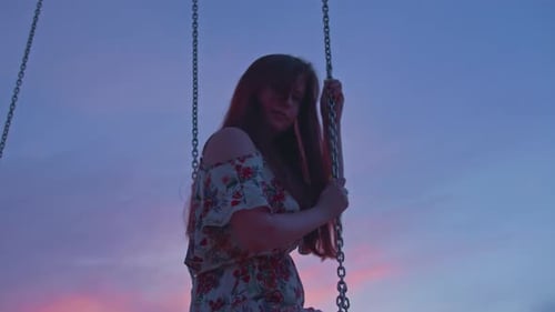 Auburn Haired Woman Sits on Swing at Sunset