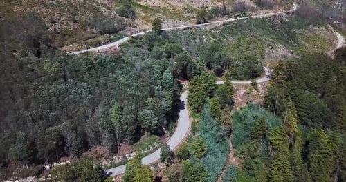 Small white caravan going up a road on the side of the mountains in Portugal , shot on drone.