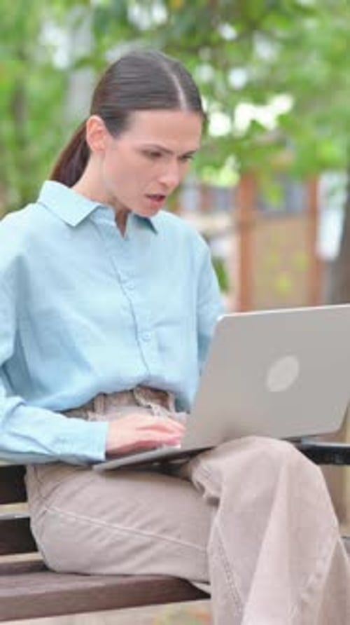 Woman Shocked by Loss on Laptop Outdoor