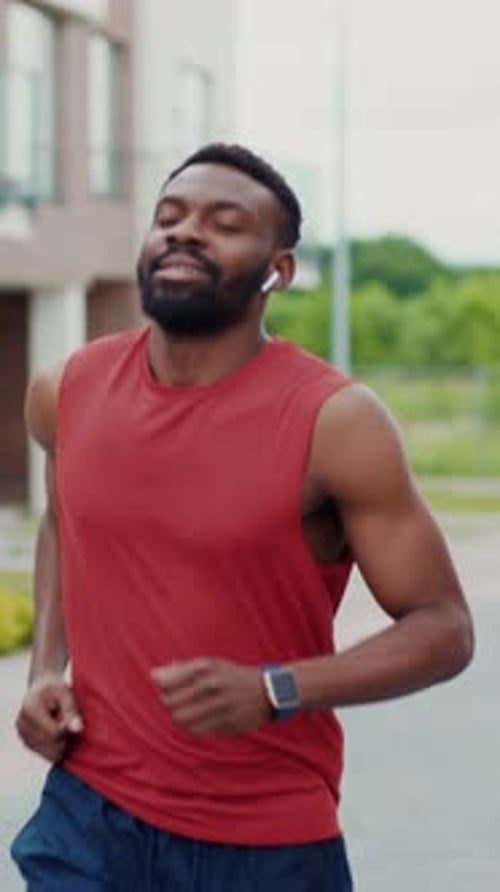 Athletic Man Running Outside Wearing Wireless Earphones