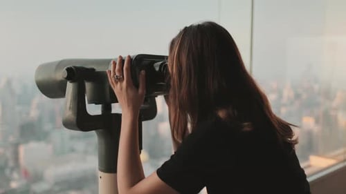 Woman Looks Through City Binoculars on Skyscraper
