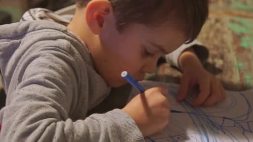 Close up of Caucasian toddler boy drawing with colour markers on paper