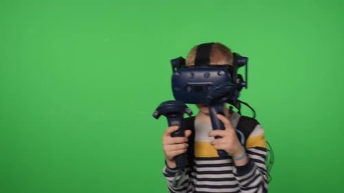 A Boy in a Virtual Reality Headset is Playing a Sword Game on a Green Background