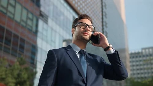 Closeup smiling man talking mobile phone outside office building. Close up of cheerful businessman h