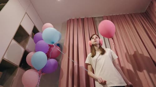Girl Holds Colorful Balloons in Cozy Room