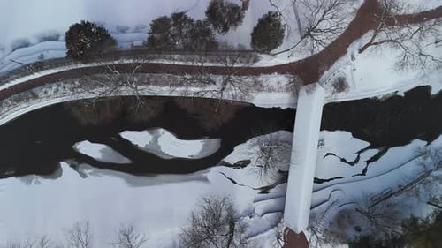 Aerial Top Down Shot of a Winter River the Bridge are Covered with Snow