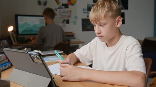 Teenager macht Hausaufgaben mit Tablet und bittet älteren Bruder um Hilfe