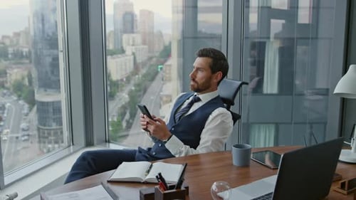 Serious businessman texting message on smartphone in modern office workplace