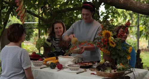 People Enjoying Meal Outdoors Surrounded by Vegetables