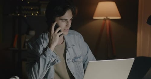 Ambitious Businessman Working with Laptop Speaking on Mobile Phone and Checking Documents in Office