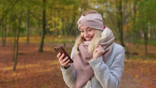 Cheerful Young Lady Walking in Park in Autumn