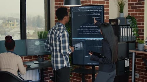 Softwareentwickler analysiert Code auf einem großen Office-Display