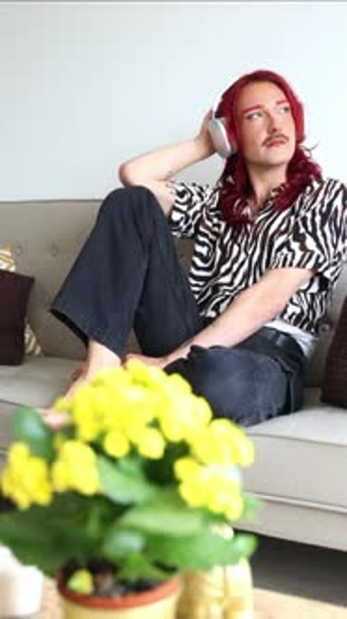 vertical Non-binary person listening to music with headphones on a sofa