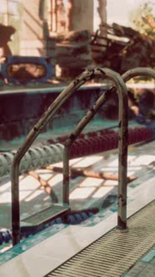An Abandoned Swimming Pool with a Rusted Metal Railing