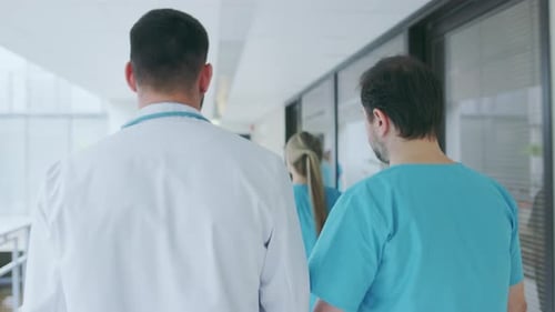Nachfolgende Rückansicht eines Arztes und eines Chirurgen, die es eilig haben, durch den Krankenhauskorridor zu gehen. Medi