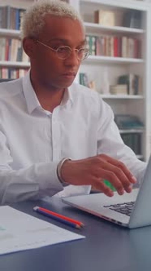 Jeune homme afro-américain concentré travaillant sur un ordinateur portable dans un bureau lumineux