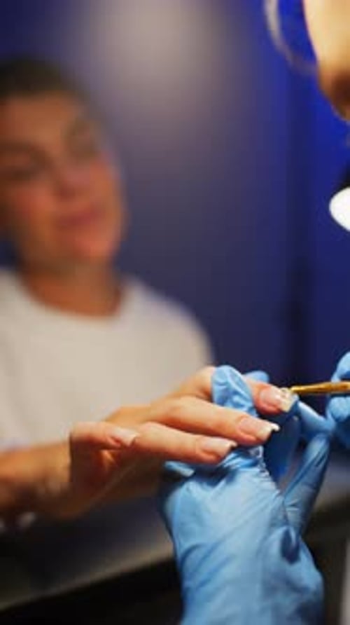 Woman getting manicure with blue gloved aesthetician