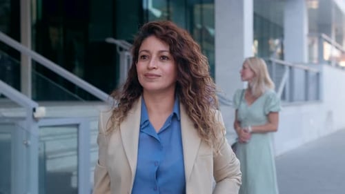 Businesswoman walking in front of modern office building.