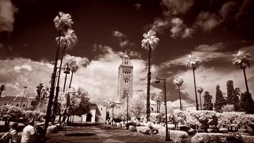Monotone, wide shot time-lapse of clouds sailing by the Koutoubia Mosque in Marrakech, Morocco. Shot