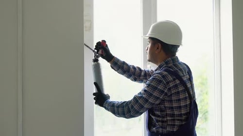 Construction Worker Sealing Window with Insulating Foam