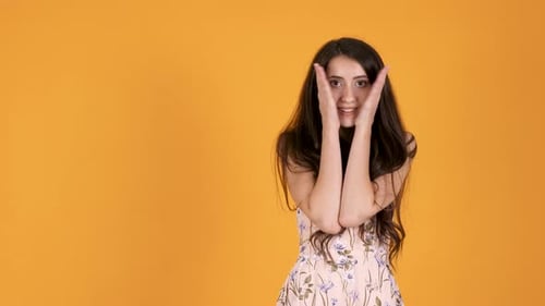Woman Plays Peek-a-Boo Against Orange Background