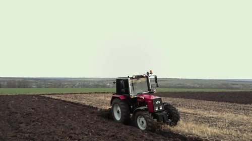 Red tractor plowing the field in Ukraine