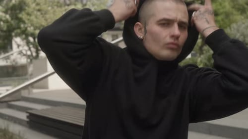 Street dancer performs a dance, making expressive movements with tattooed hands.