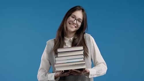 Asian Clever Student Holds Stack of University Books From College Library on Blue Background