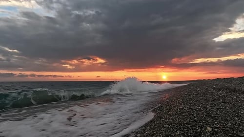 Während des herrlichen Sonnenuntergangs werden Wellen am leeren Kiesstrand angespült. Aufnahme auf dem Stativ
.