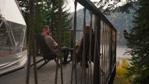 Man and Woman Relaxing on Rustic Deck Overlooking Lake