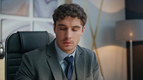 Man Typing on Laptop, Reviewing Documents in Office
