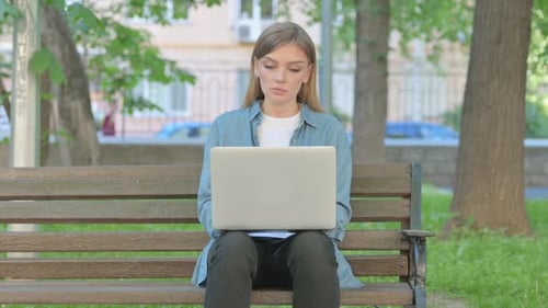 Woman Typing on Laptop while Sitting on Bench in Park