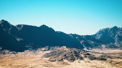 Midday Scene of Desert Basin Surrounded By Jagged Mountain Ridges