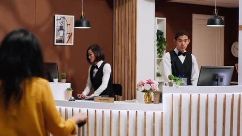 Asian Hotel Staff Greeting Customer at Front Desk Entrance