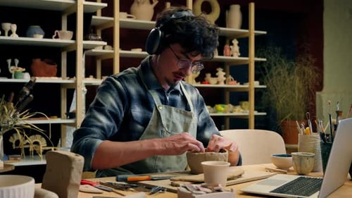 Relaxed Caucasian Man Male Guy Headphones Listen Music Artist Designer Potter Sculptor in Art Studio