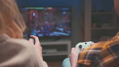 Unrecognizable Couple Playing Fighting Video Game on Couch at Night