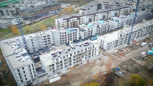 Survol aérien d'un site de développement de nouvelles constructions avec des grues à haute tour qui construisent des biens immobiliers.