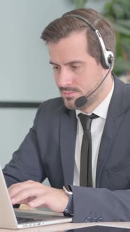 Businessman with Headset Working on Laptop, vertical video