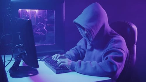 hacker in a hood works at a computer