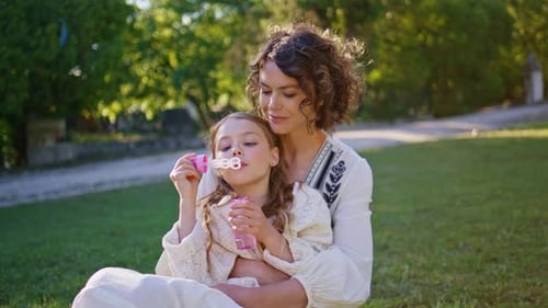 Parent Kid Blowing Soap Colorful Bubbles in Green Sunny Park Together Portrait