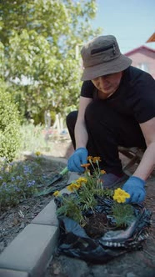 Woman Preparing Flowers for Planting in Garden Bed