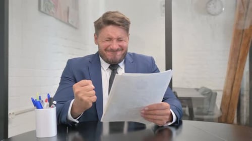 Frustrated Man Reviewing Papers in Corporate Office